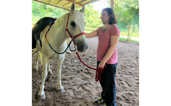 photo d'un patient qui tient par la longe un cheval blanc lors d'une séance d'équithérapie
