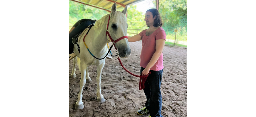 photo d'un patient qui tient par la longe un cheval blanc lors d'une séance d'équithérapie